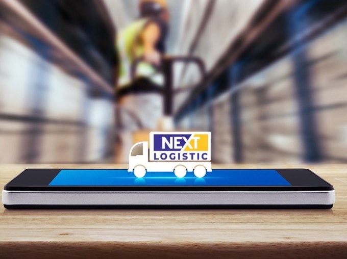 Склад с мобилен телефон и камион на nextlogistic върху него